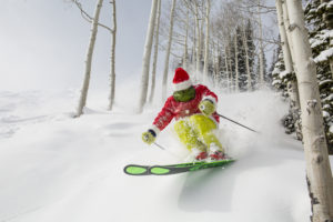 Someone dressed as the grinch skiing during the holiday season.