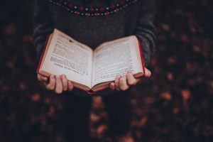 A person holding an open book and reading.