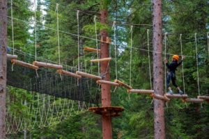 A person balancing on logs at the Lost Forest adventure park near the Limelight Hotel Snowmass.