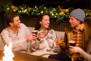 A group of happy guests at Limelight Hotel sitting by the fire- après-ski in the Limelight Lounge
